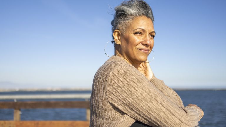 Woman standing on a dock by the ocean reflecting on the new year