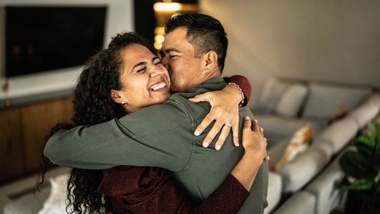 Newlywed couple hugging each other in their home