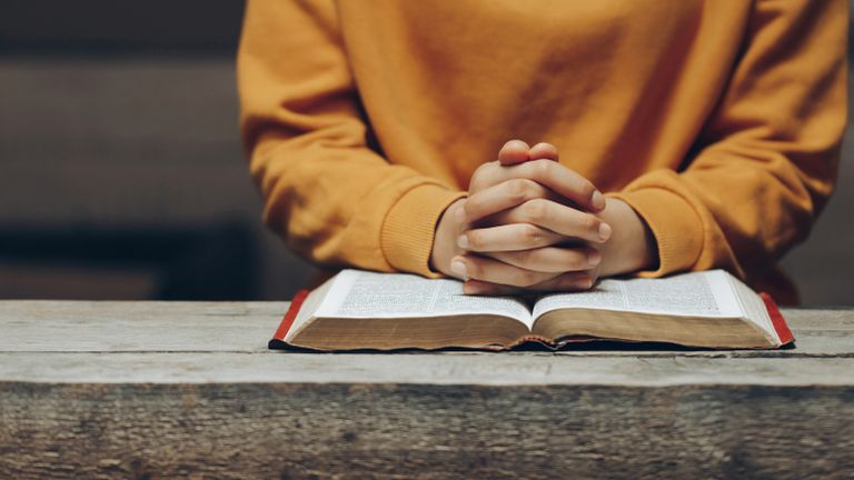 Woman in yellow sweater reading her bible about why is it called lent