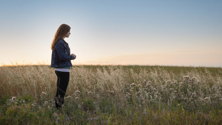 Young woman praying in a spring field