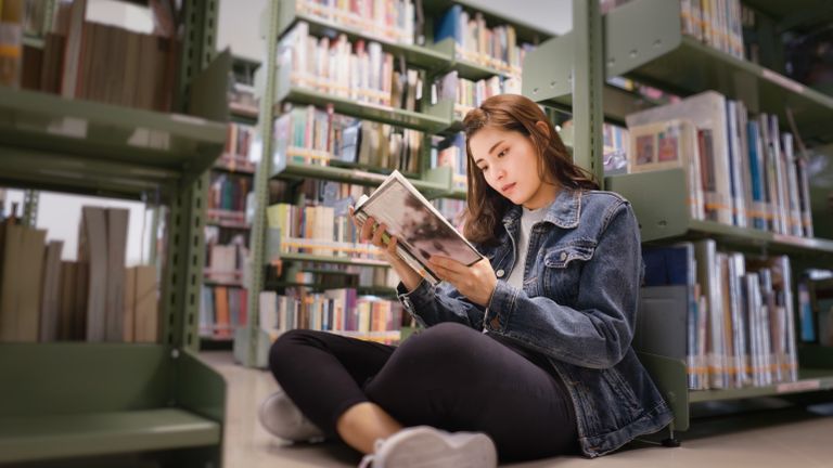Woman sitting on the ground doing her reading habit at the library