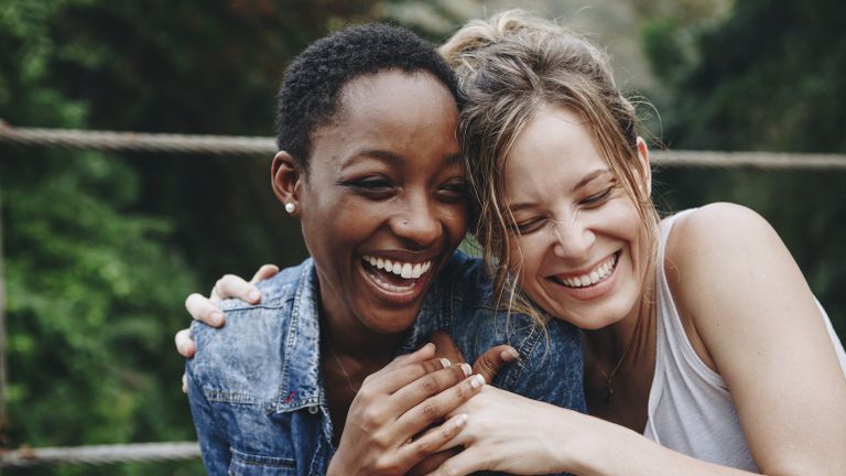 Two women friends laugh together to celebrate types of valentines
