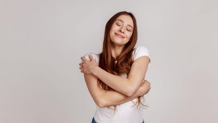 Woman on a white background hugging herself as a type of valentine