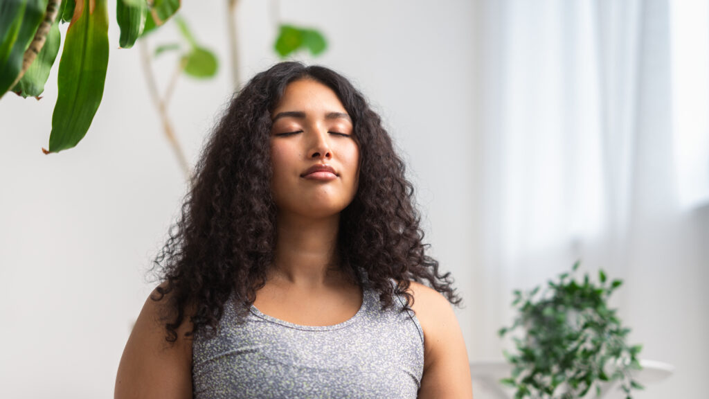 A woman in workout clothes meditating at her daily positive habit