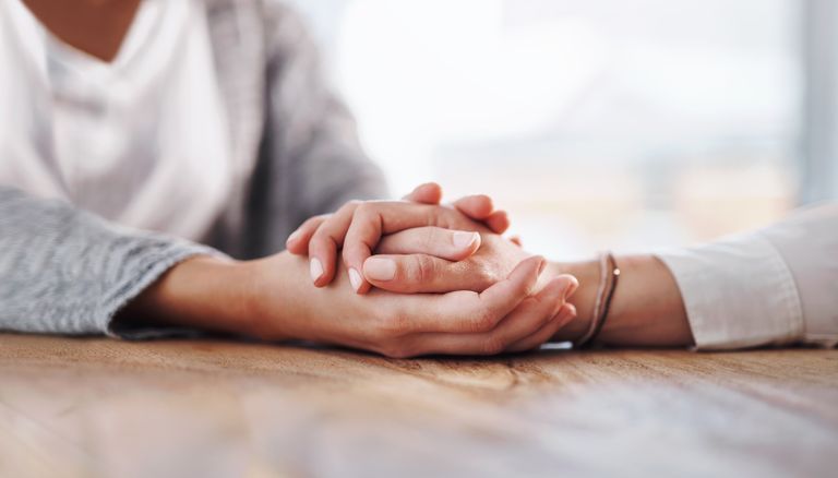 Person holding another person's hands for their comforting bible habits