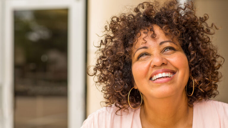 Woman looking up at sky and smiling at quotes about happiness from within