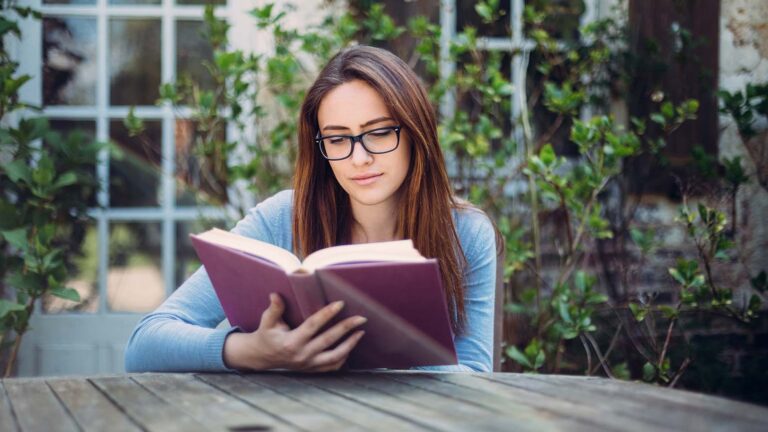 Woman at an outside table reading palm Sunday scriptures in the Bible