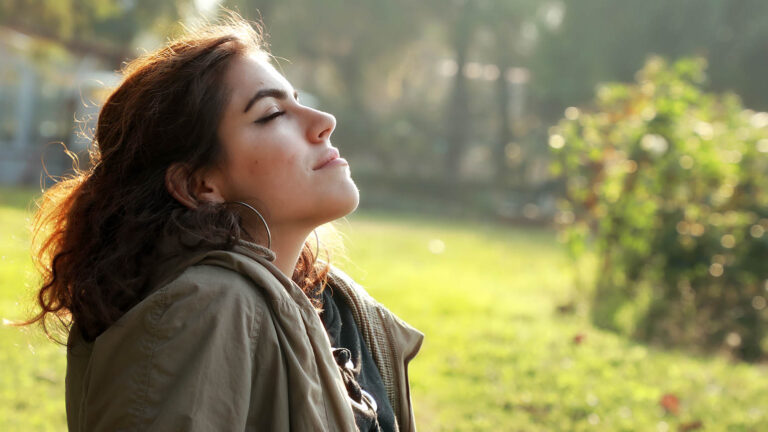 Woman does a spring activity of praying with her eyes closed in a garden