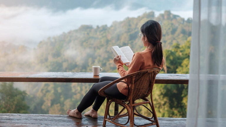 Woman sits by a view reading about spring activities