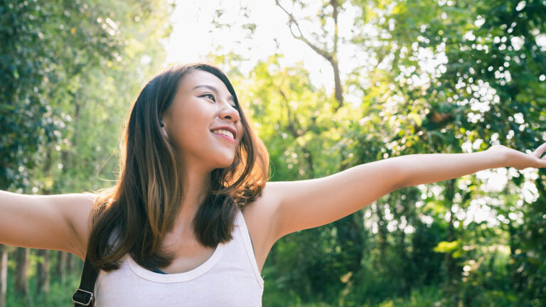 Woman with her arms up going on a walk for her spring activity